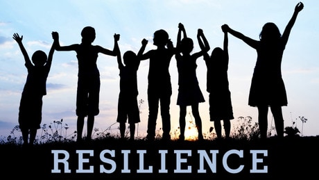 A group of silhouetted people standing in a field, above a sign that says - Resilience